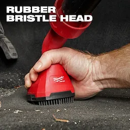 A person grips the AIR-TIP™ Swiveling Palm Brush with a rubber bristle head, ideal for cleaning. The red brush features the Milwaukee logo and is designed for easy handling. The text "RUBBER BRISTLE HEAD" is displayed at the top left of the image.