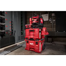 Milwaukee Packout rolling tool chest stacked with tool boxes and a backpack in an industrial room.
