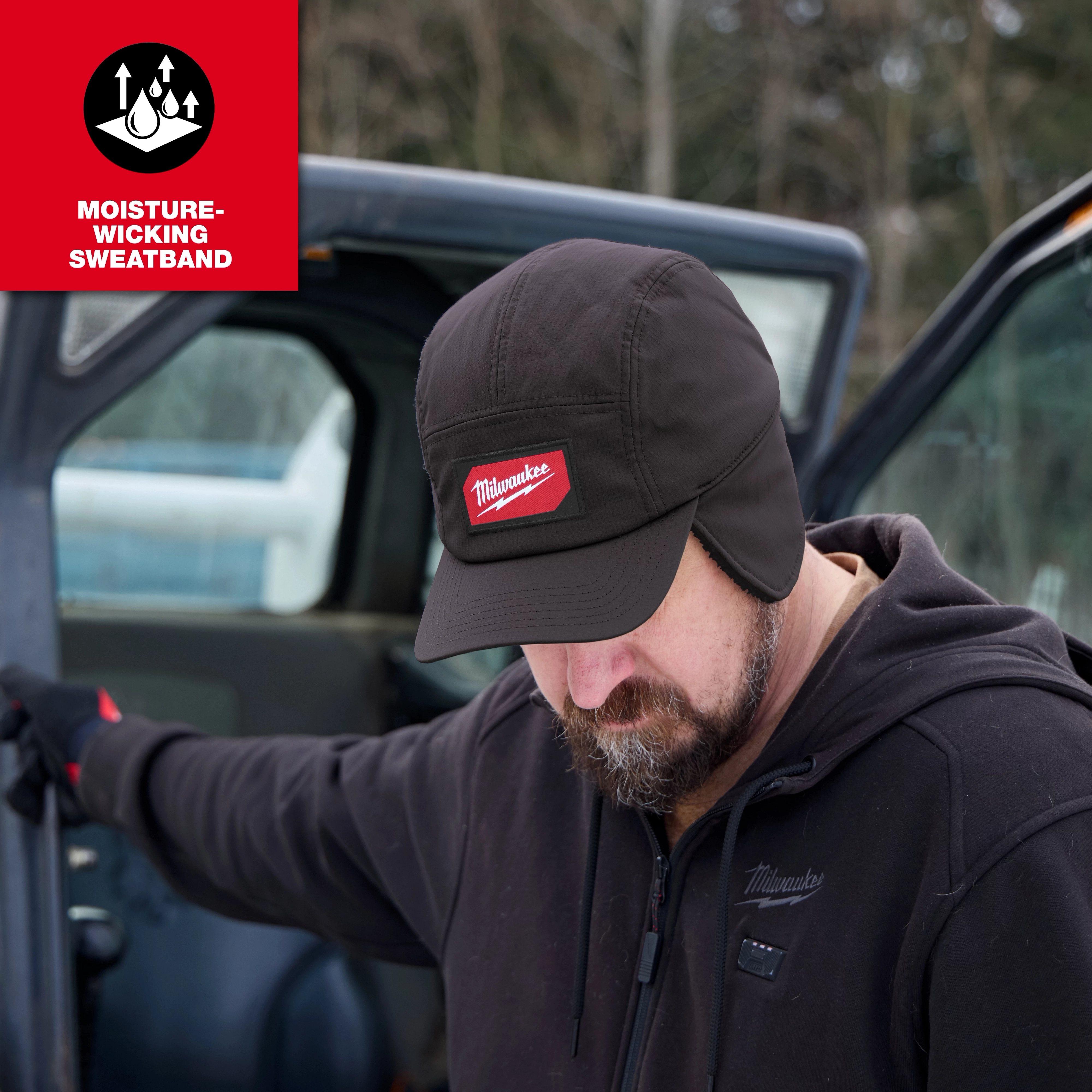 Person wearing a Milwaukee Sherpa-Lined Hat while standing beside an open vehicle door.
