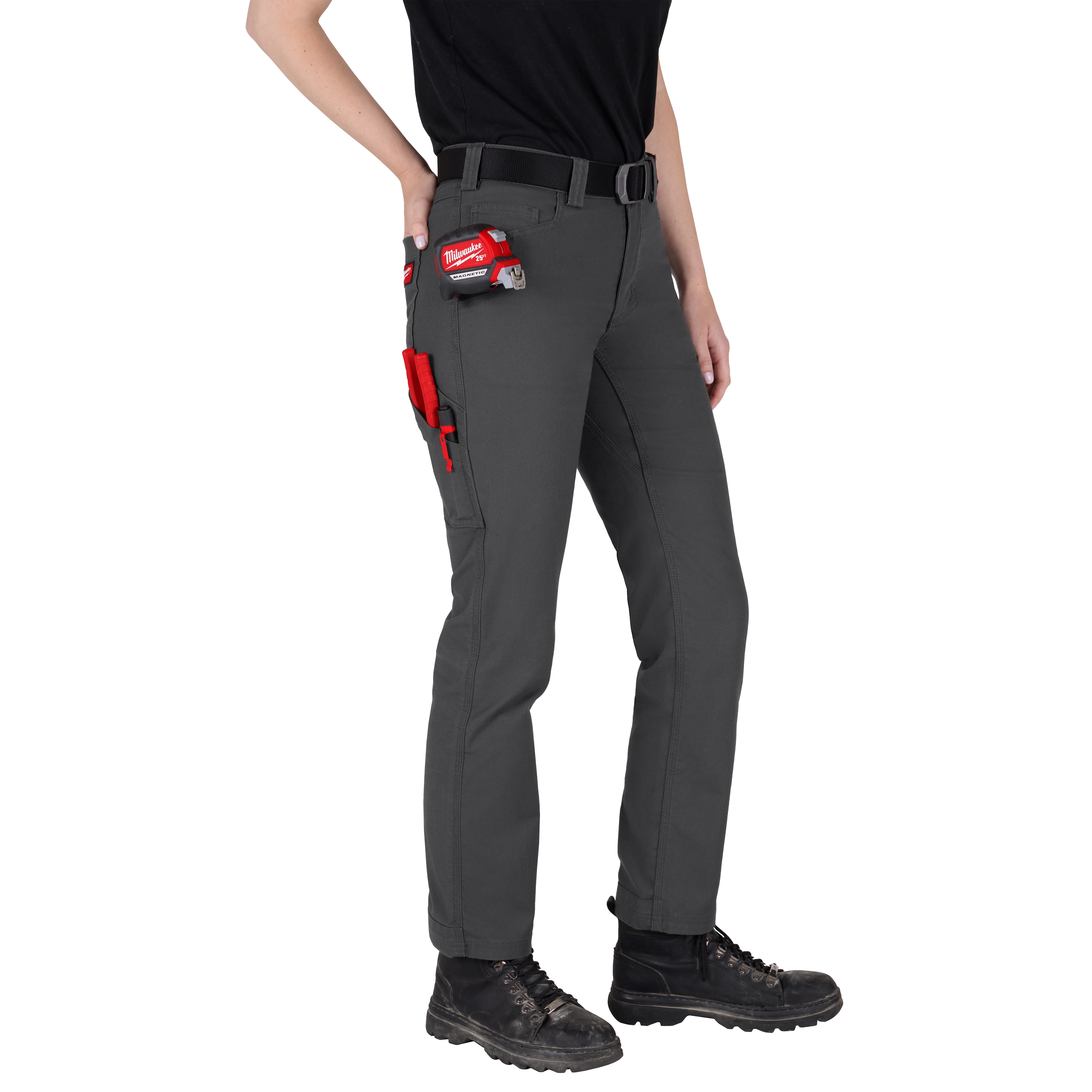 A person wearing Women's Work Pants - Gray, featuring durable material and multiple pockets, is shown from waist to ankle. The pants have a black belt and tools in the pockets. The person is also wearing black work boots and a black shirt.