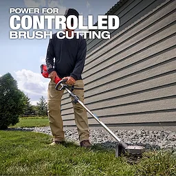 Person using an M18 FUEL QUIK-LOK Reciprocator Attachment to trim grass beside a building.