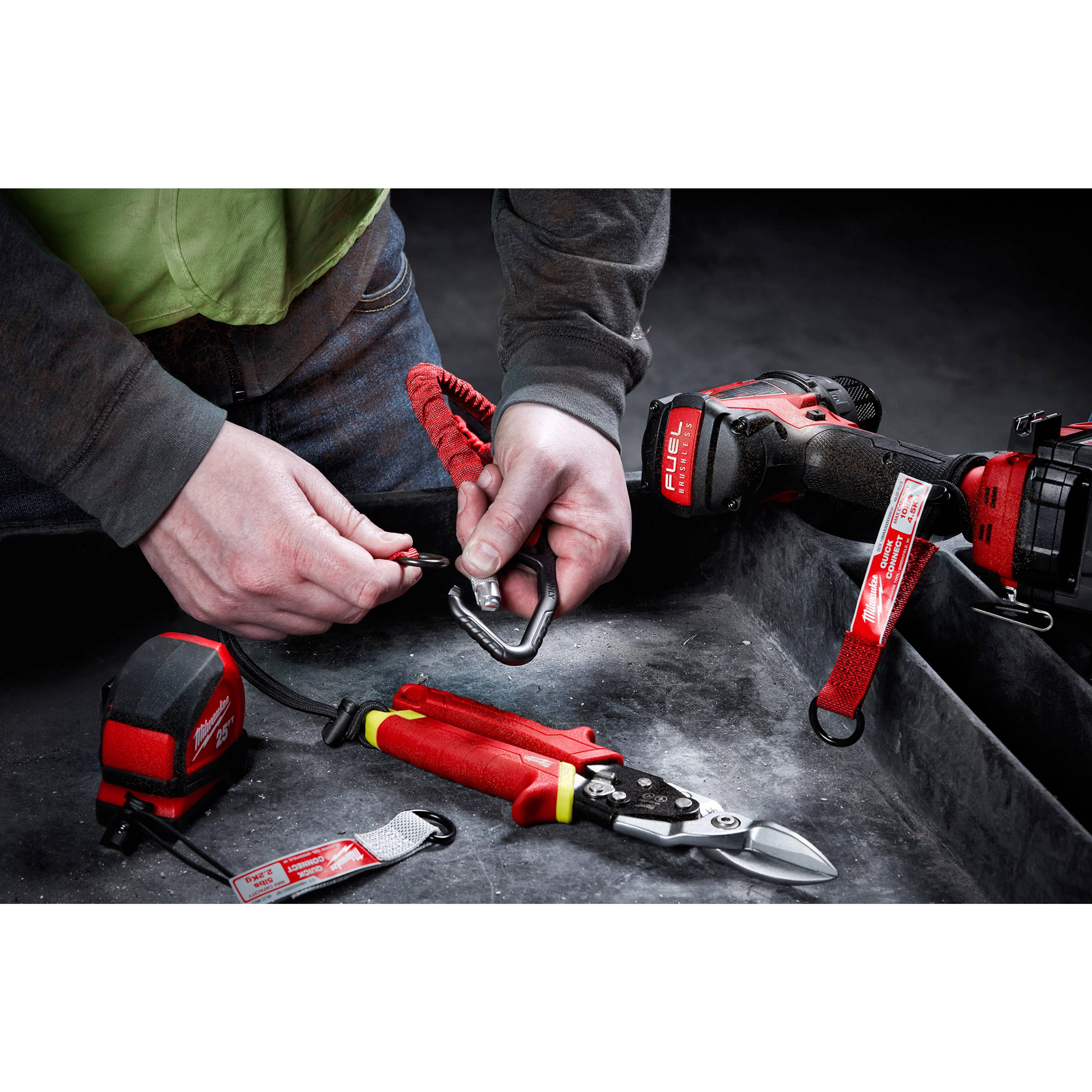 Person using the 10 LB QUICK-CONNECT Locking Tool Lanyard with various red and black tools on a dusty surface.
