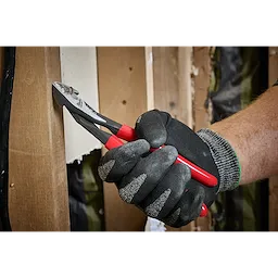 A hand wearing dark gloves uses the Knipex Diagonal Cutter to cut an object. The Knipex Diagonal Cutter has red and black handles and is designed for cutting wires and other materials.
