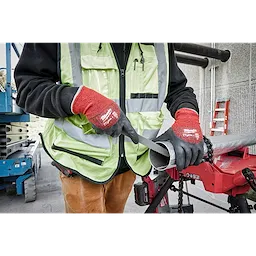 Person wearing Cut Level 4 Winter Dipped Gloves - L working on a metal pipe outdoors, using a hand file for deburring.