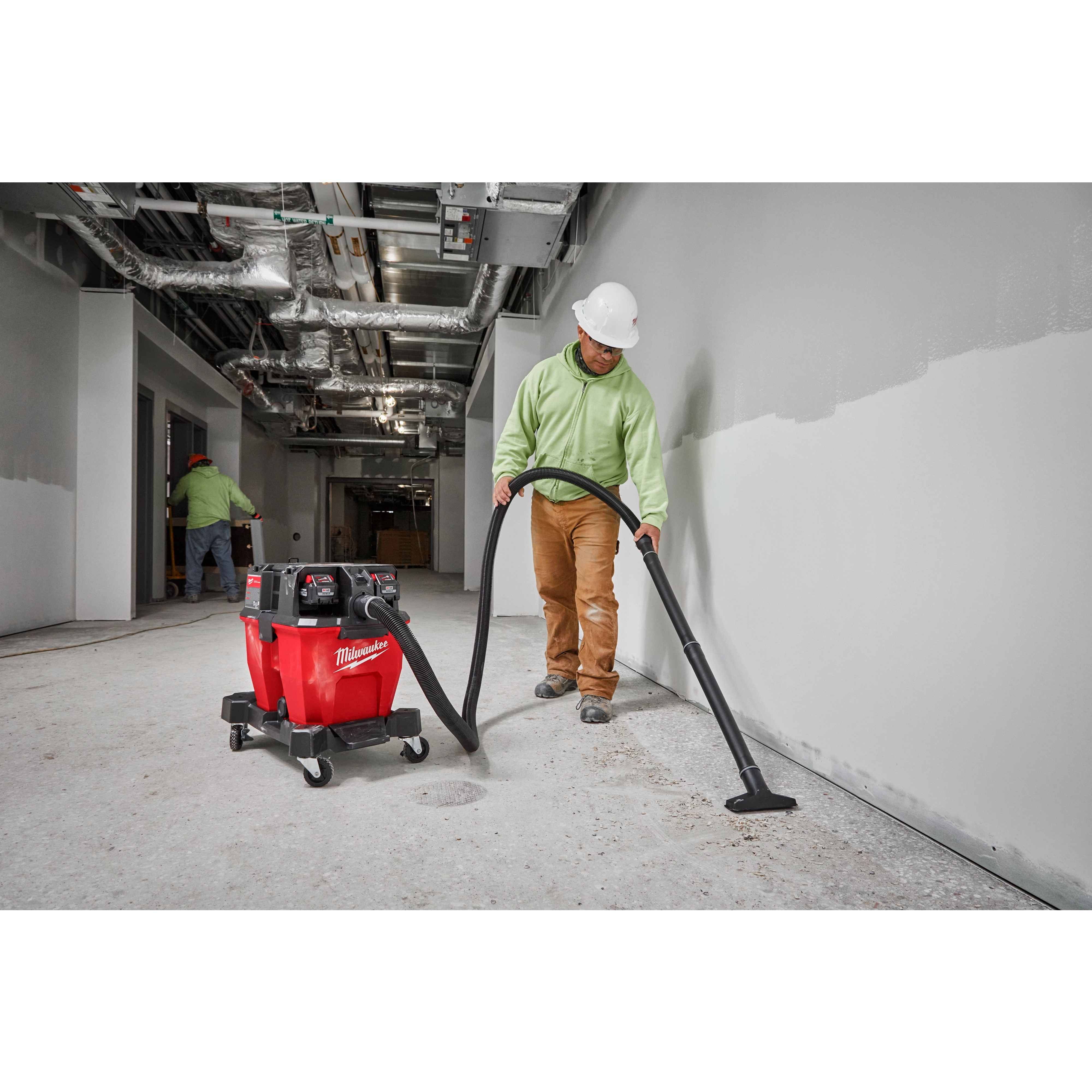 Worker using the Milwaukee M18 Fuel 9 Gallon Dual-Battery Wet/Dry Vacuum to clean a construction site interior.