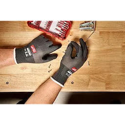 Cut Level 1 Nitrile Dipped Gloves w/ WEAR-DEFENSE Protection handling screws on a wooden workbench.