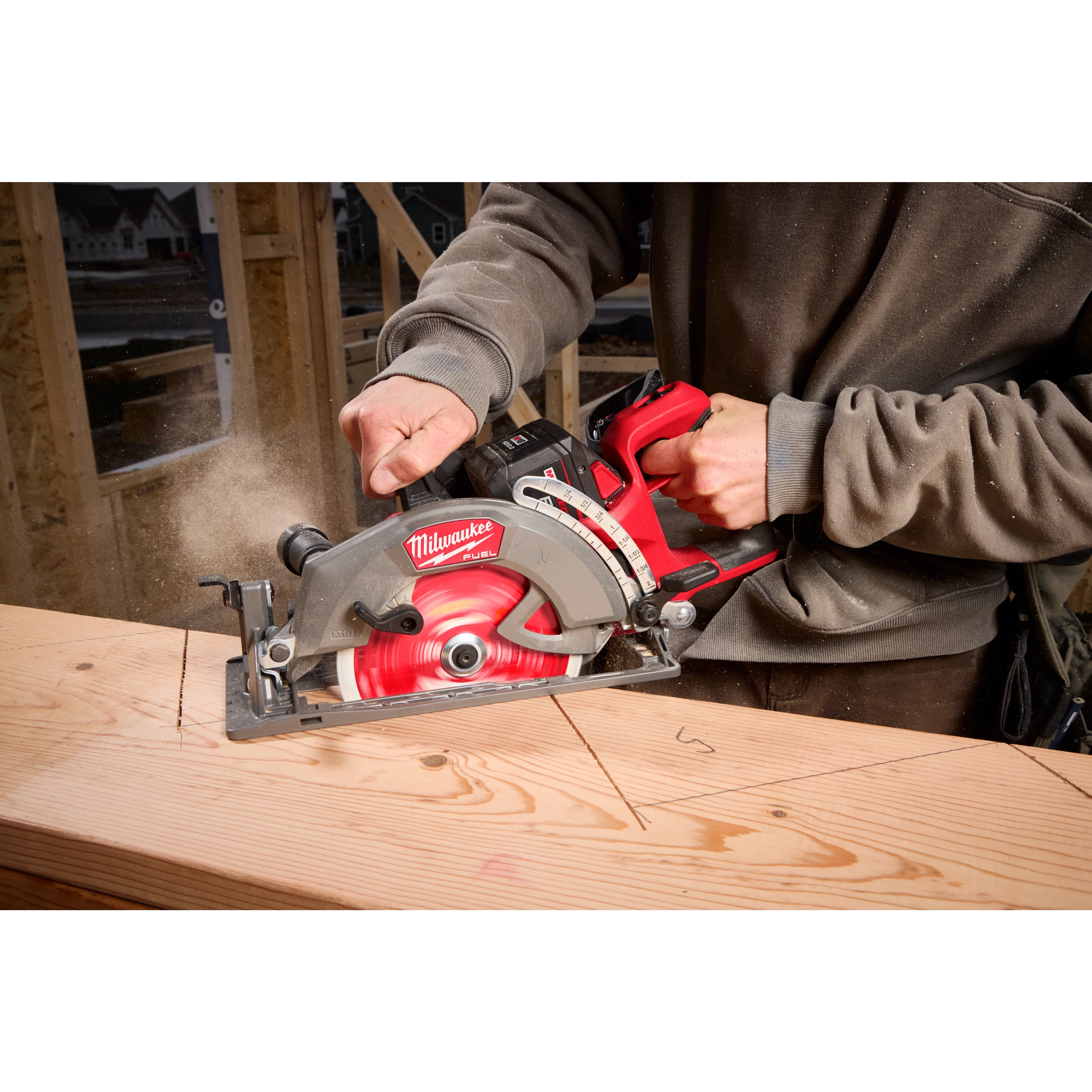 A person is using an M18 FUEL™ 7-1/4" Rear Handle Circular Saw to cut a piece of wood. The saw is red and black, and sawdust is visible in the air.