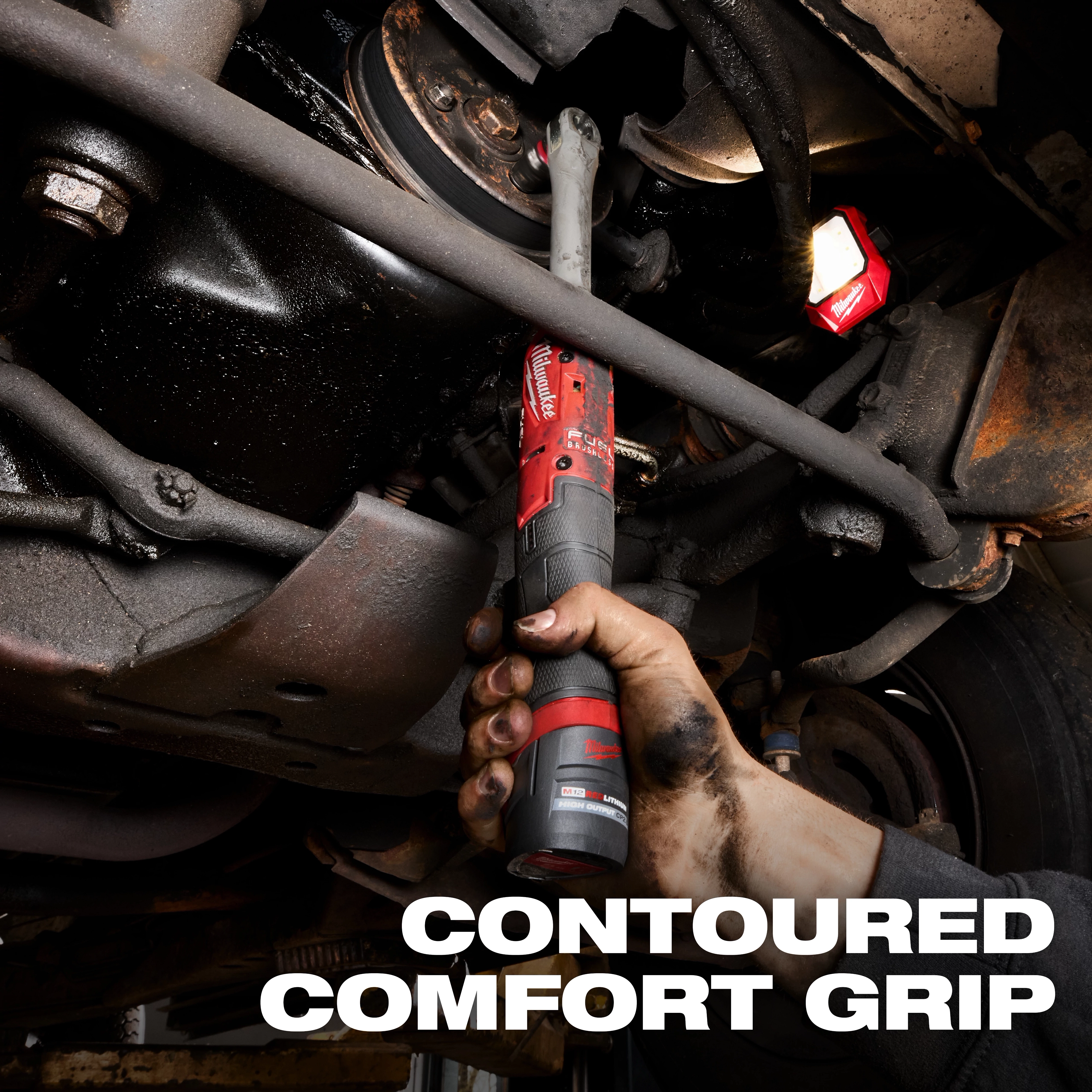 M12 FUEL 3/8" Extended Reach Ratchet held under a vehicle with bold text reading CONTOURED COMFORT GRIP.