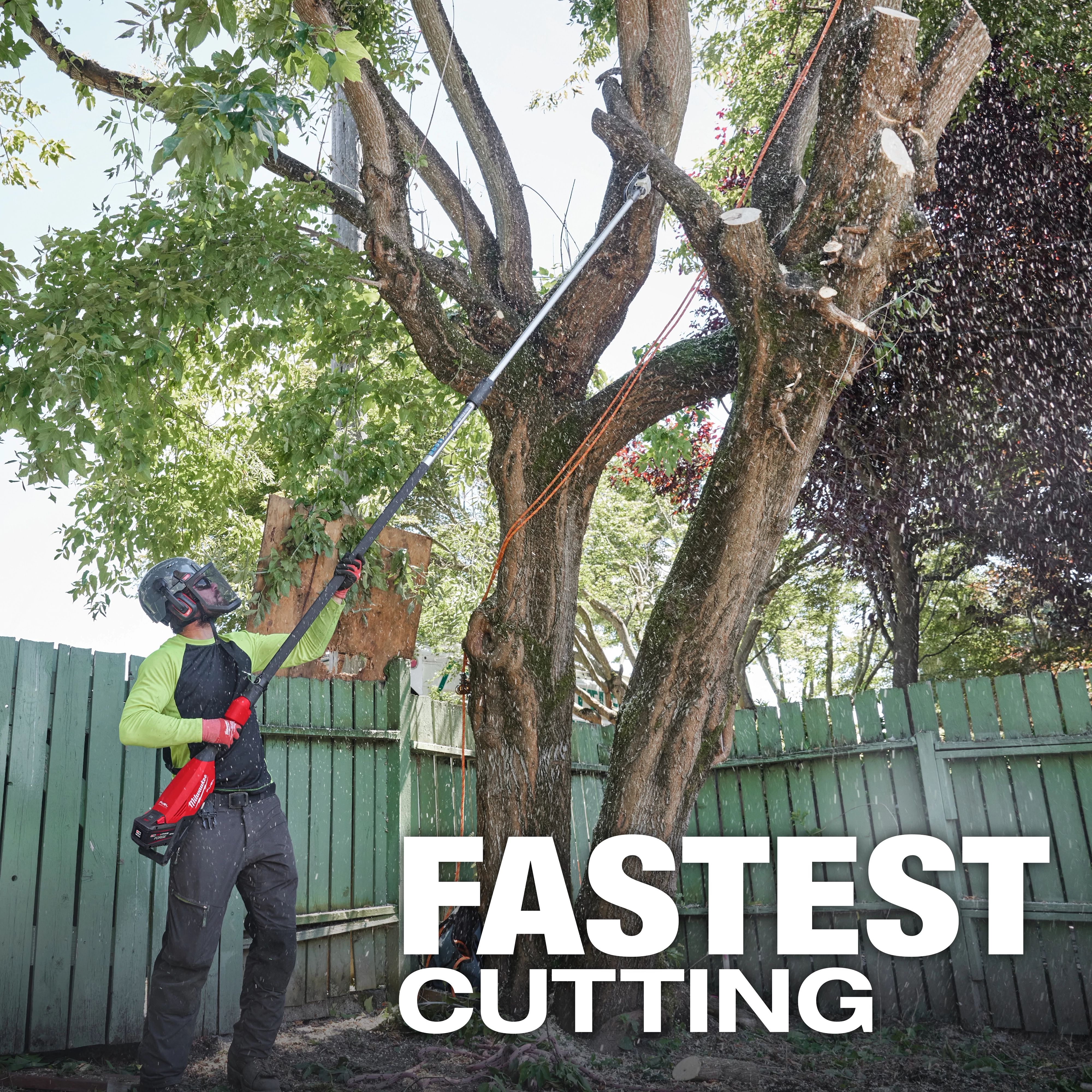 A person uses the M18 FUEL™ Telescoping Pole Saw to cut branches off a tree in a fenced yard. The image includes a text overlay that reads "FASTEST CUTTING.”