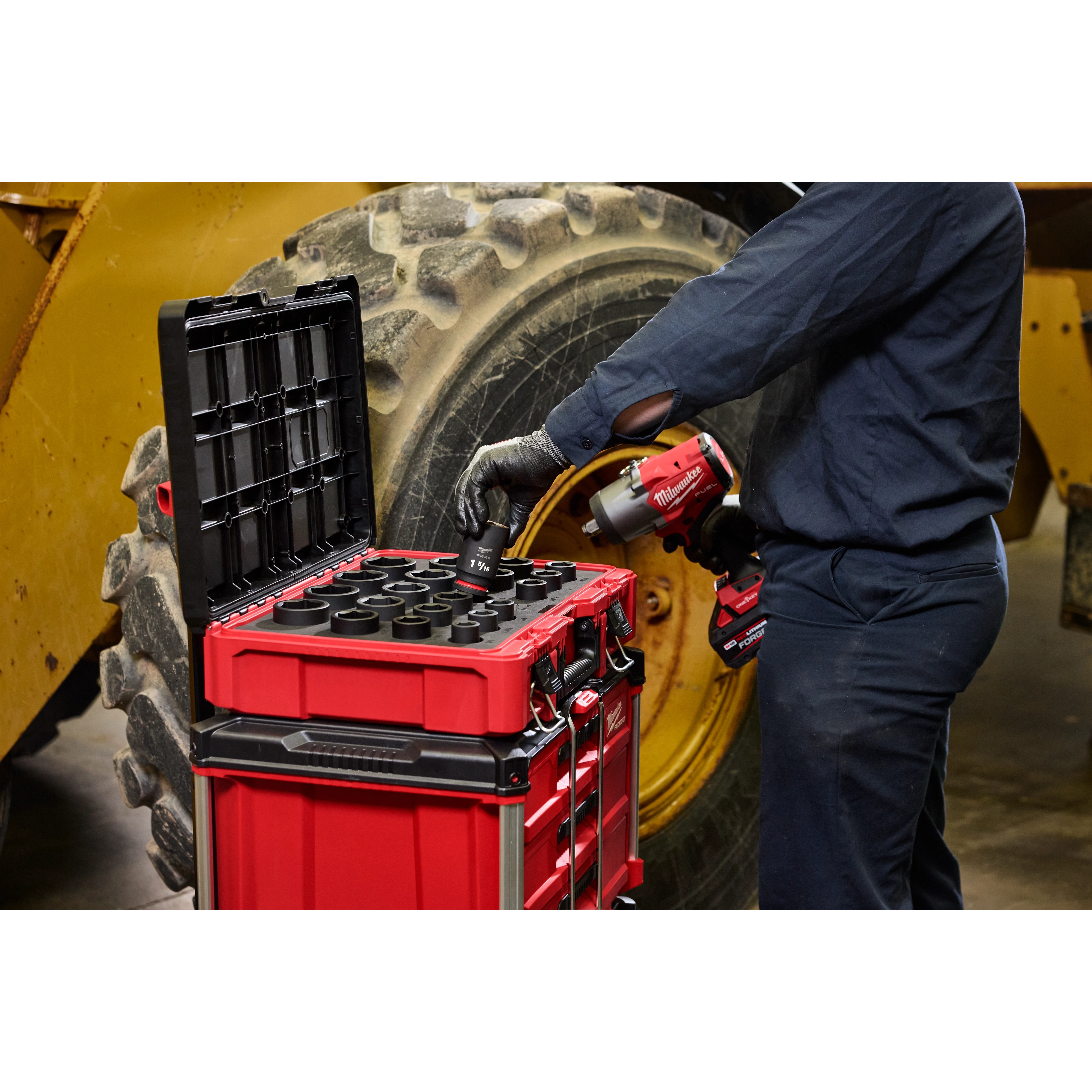Worker using 21PC SHOCKWAVE Impact Duty 3/4" Drive Metric Standard Socket Set with PACKOUT near large vehicle tire.