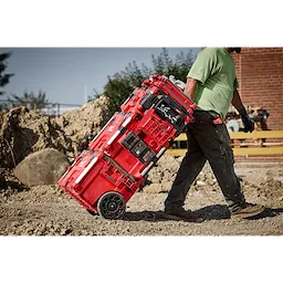 A worker transporting a PACKOUT Tool Box with PACKOUT Tool Box Compact Plate on a jobsite