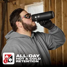 Person in a grey hoodie drinking from a PACKOUT 18oz Insulated Mug with Sip Lid in a wooden interior. Text reads "All-Day Hot & Cold Retention."
