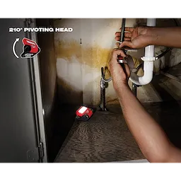 REDLITHIUM USB ROVER Pivoting Flood Light illuminating a dimly lit area under a sink while a person works on the plumbing.
