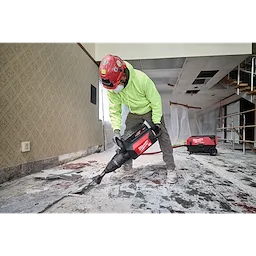 A construction worker uses the MX FUEL 27 lb SDS MAX Demolition Hammer to remove floor tiles in a partially renovated room.